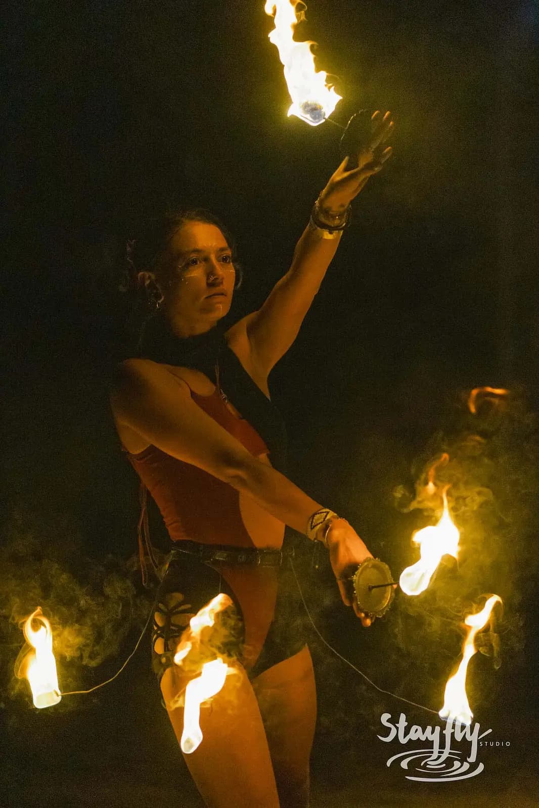 Fire performer spinning flaming poi at night.
