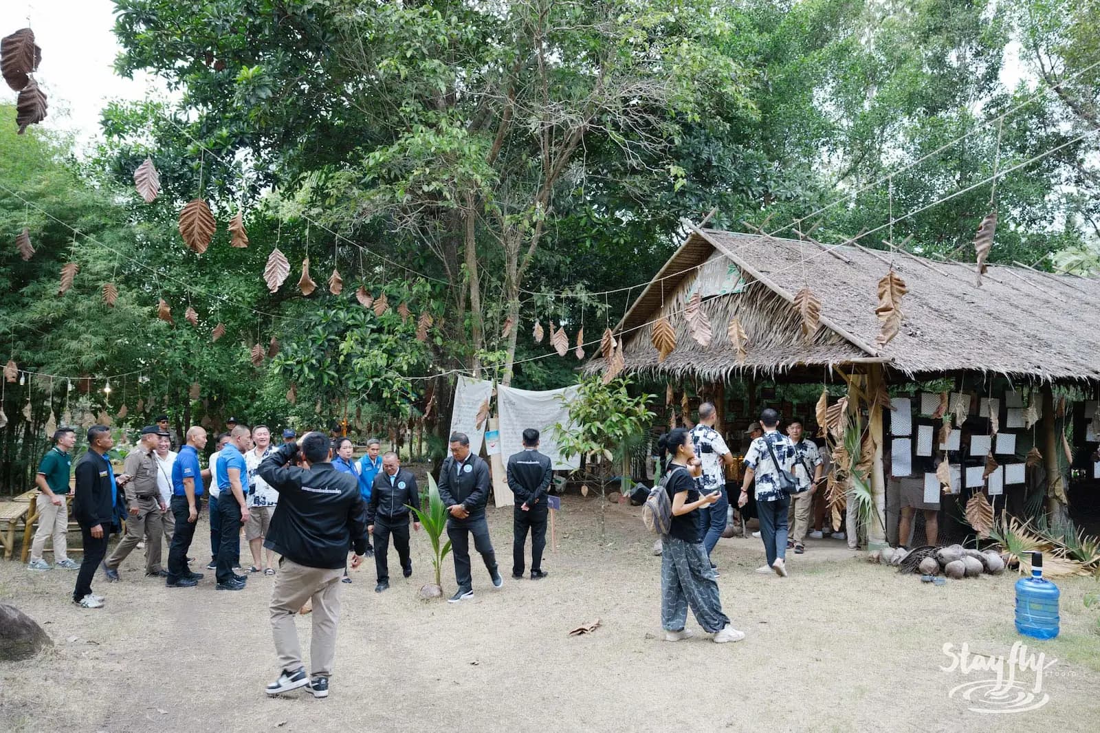 Group walking forest path near info boards and hut.