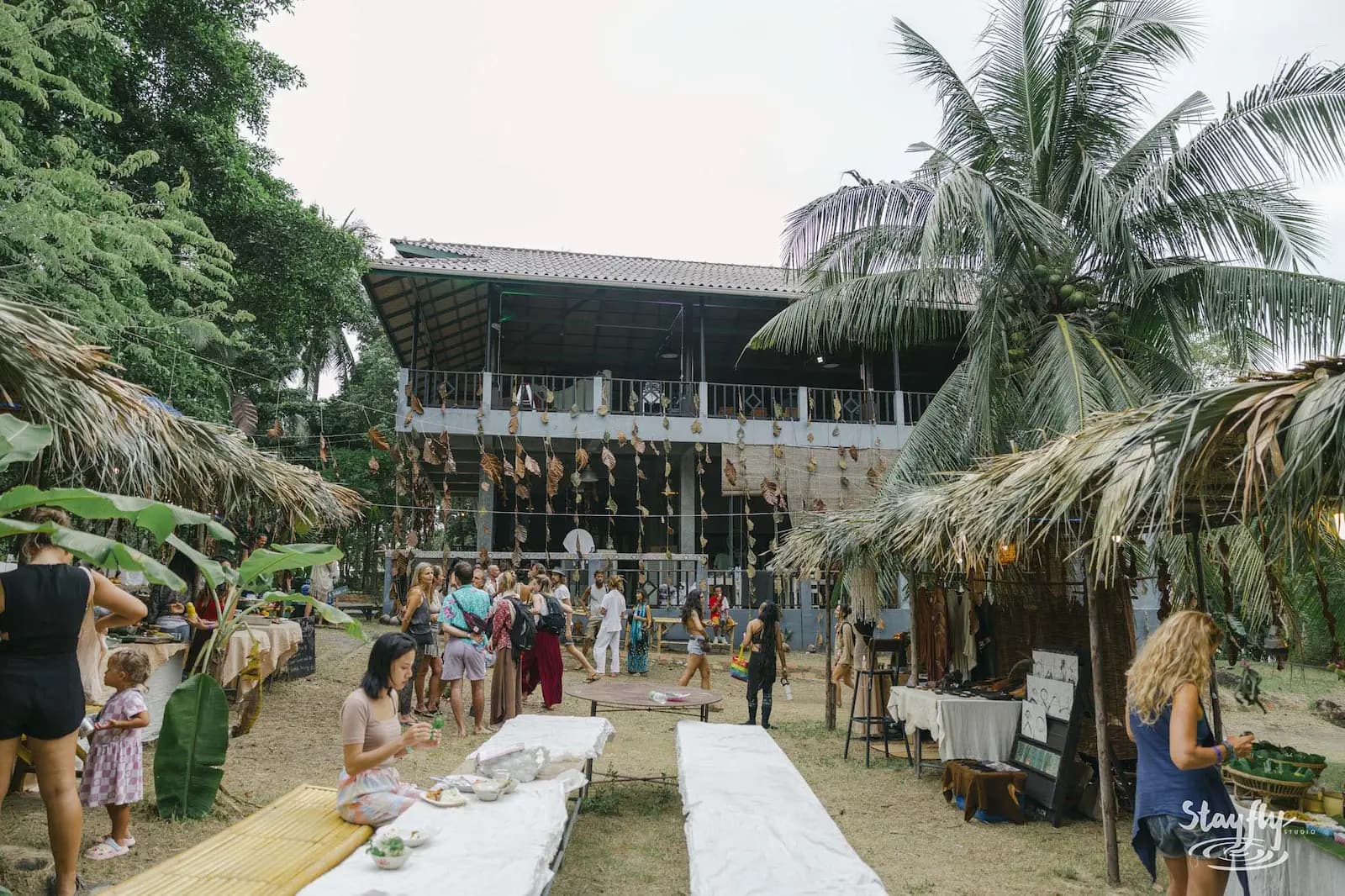 Two-story palm-roofed venue with people gathered outside.