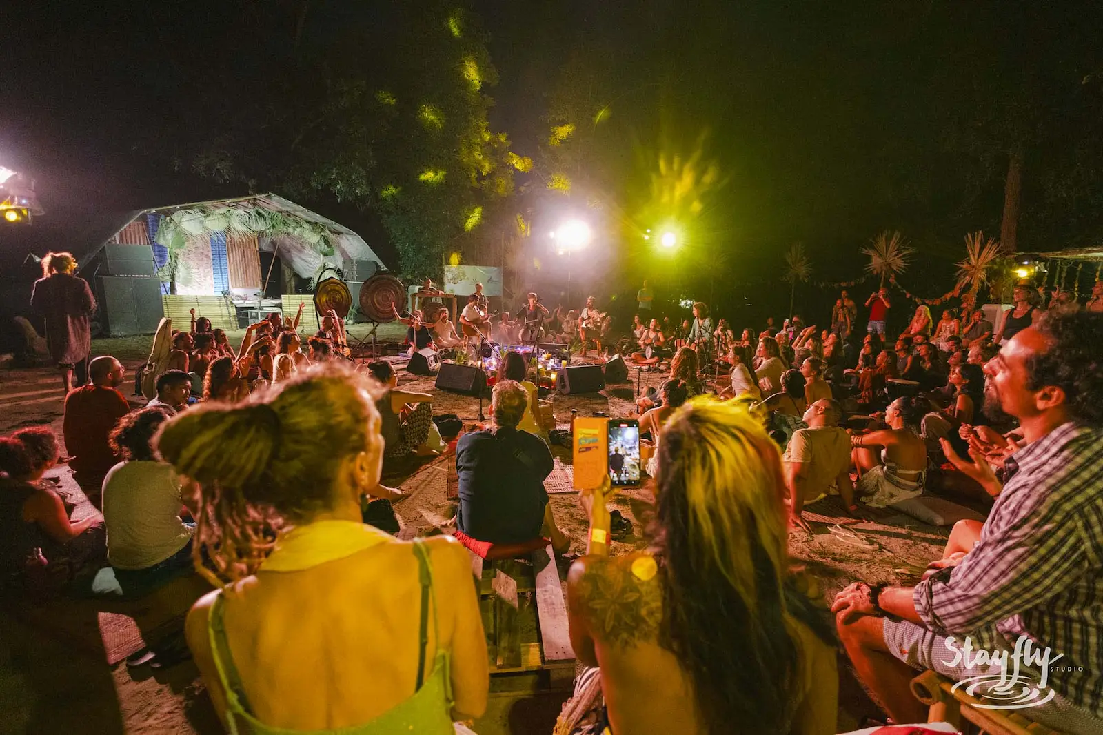 Crowd filming decorated dome tent at night.