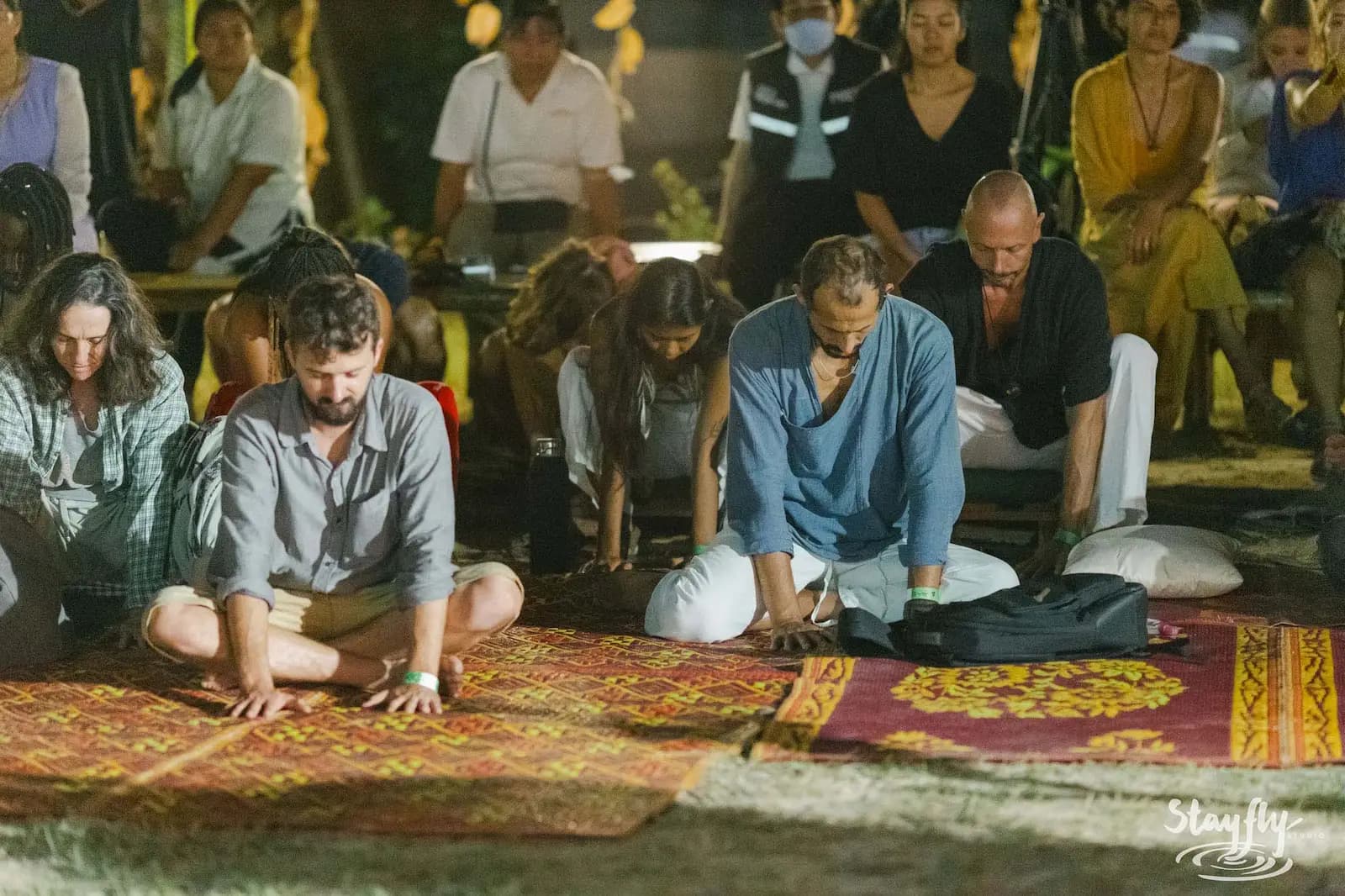 People kneeling together on mats in ceremony.