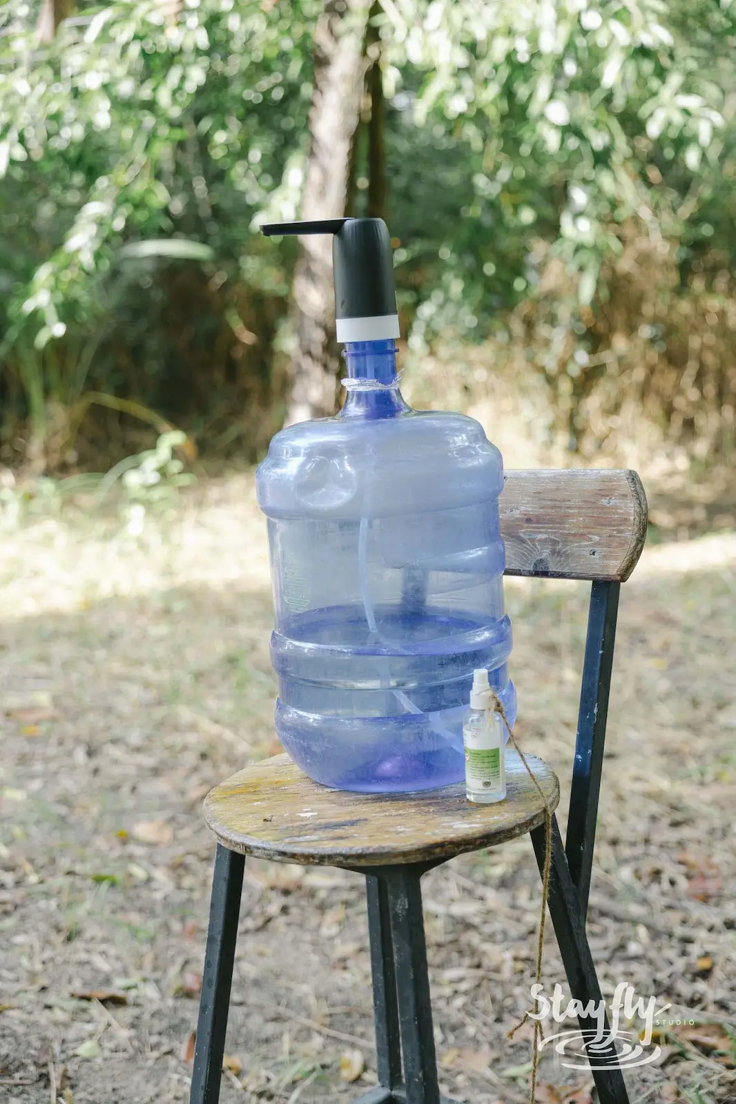Water cooler jug and dispenser on wooden stool.