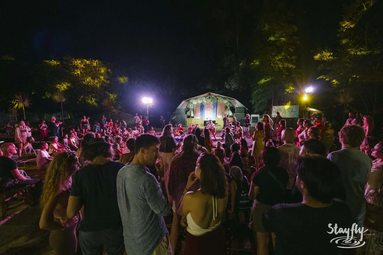 Crowd gathered near lit dome tent at night.