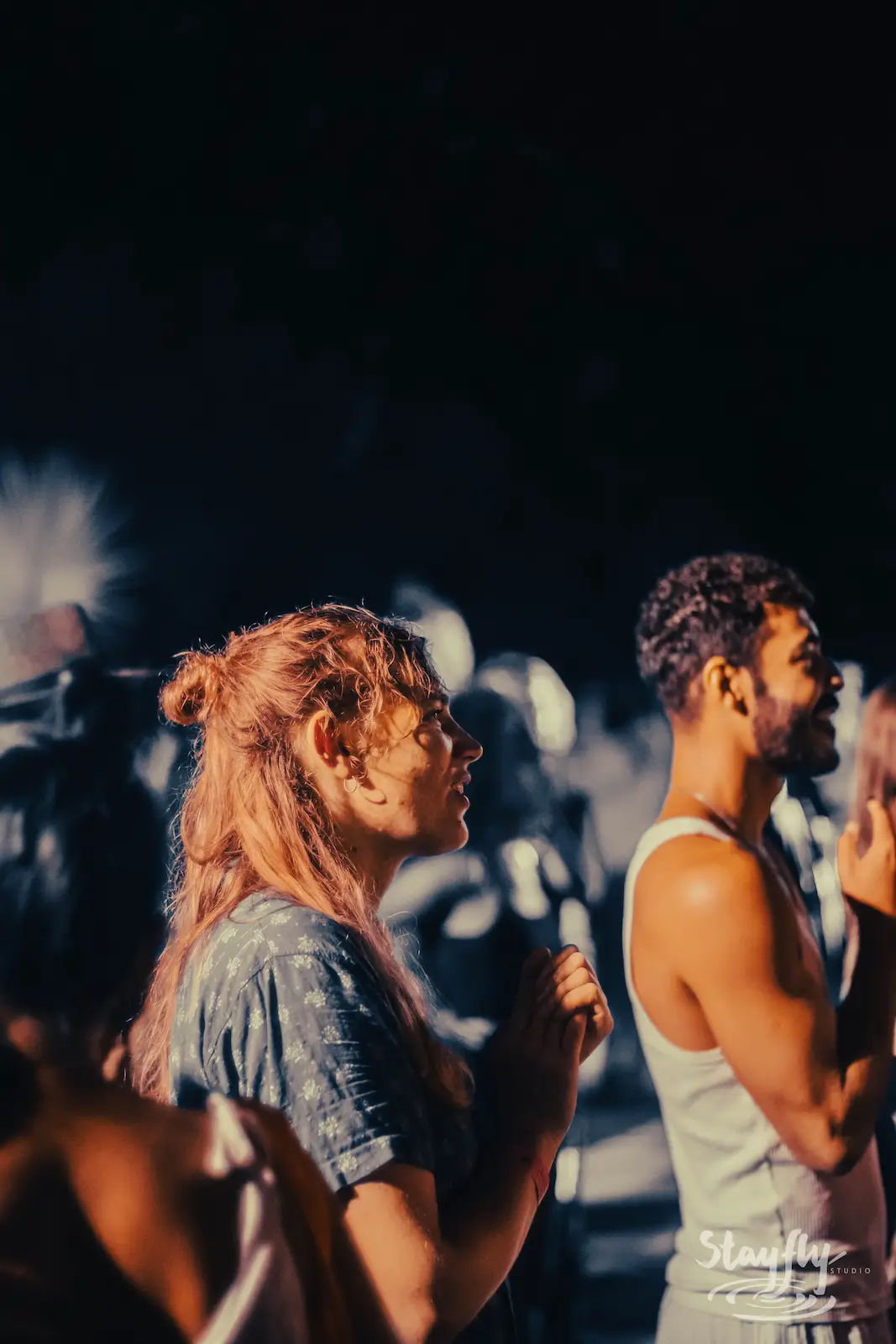 Two attendees looking up at night stage lights.