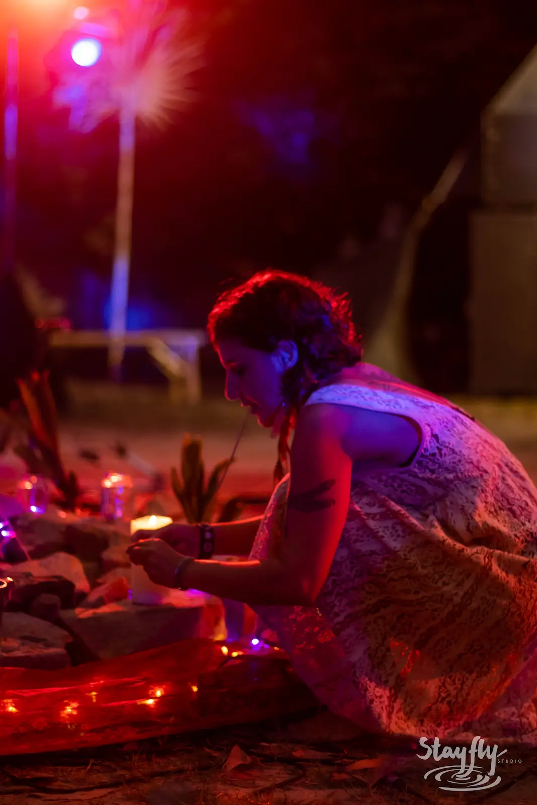 Woman lighting candles at a night altar.