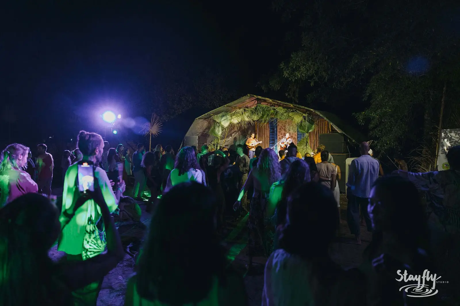 Crowd gathered near lit structure at night.