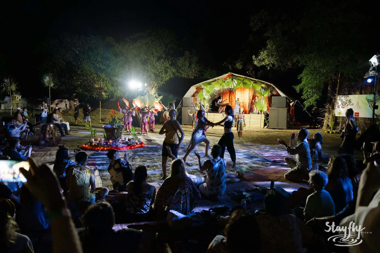 Dancers performing near lit dome tent at night.