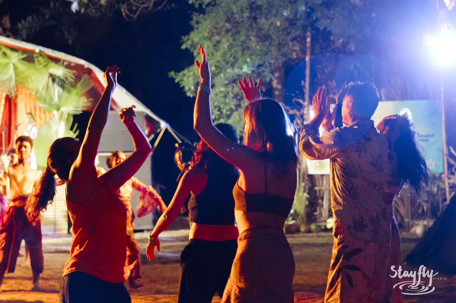 Dancers with hands raised at night gathering.