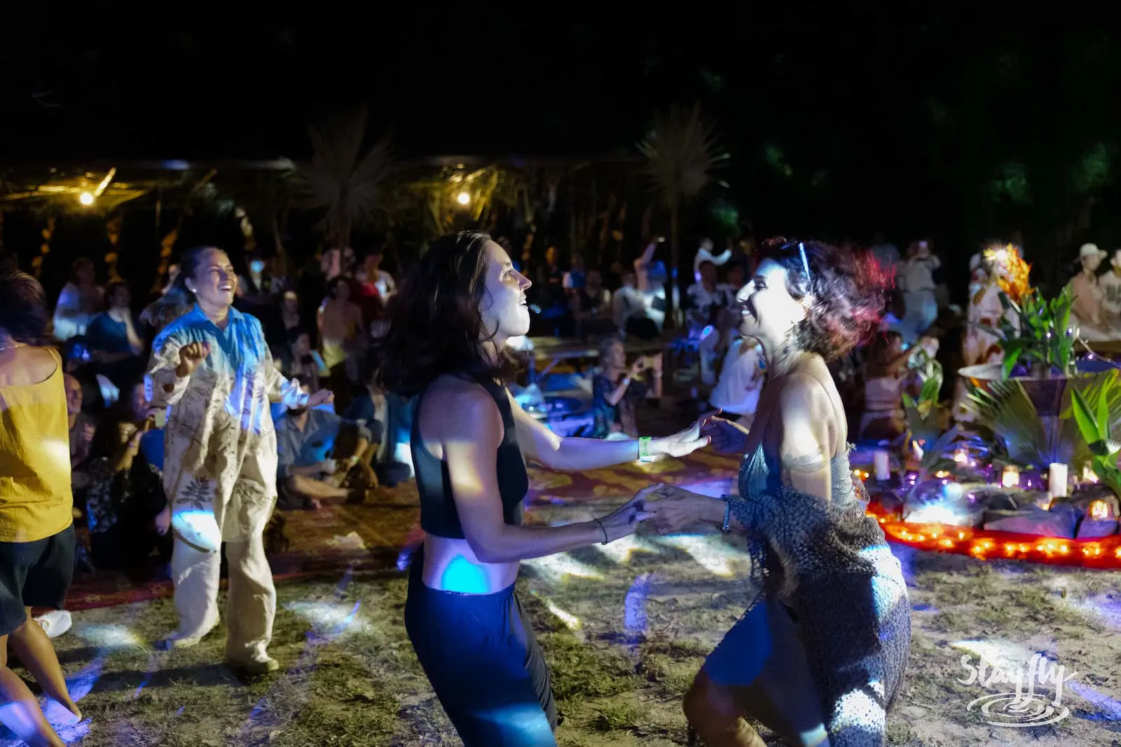 Two women dancing among LED lights at night.