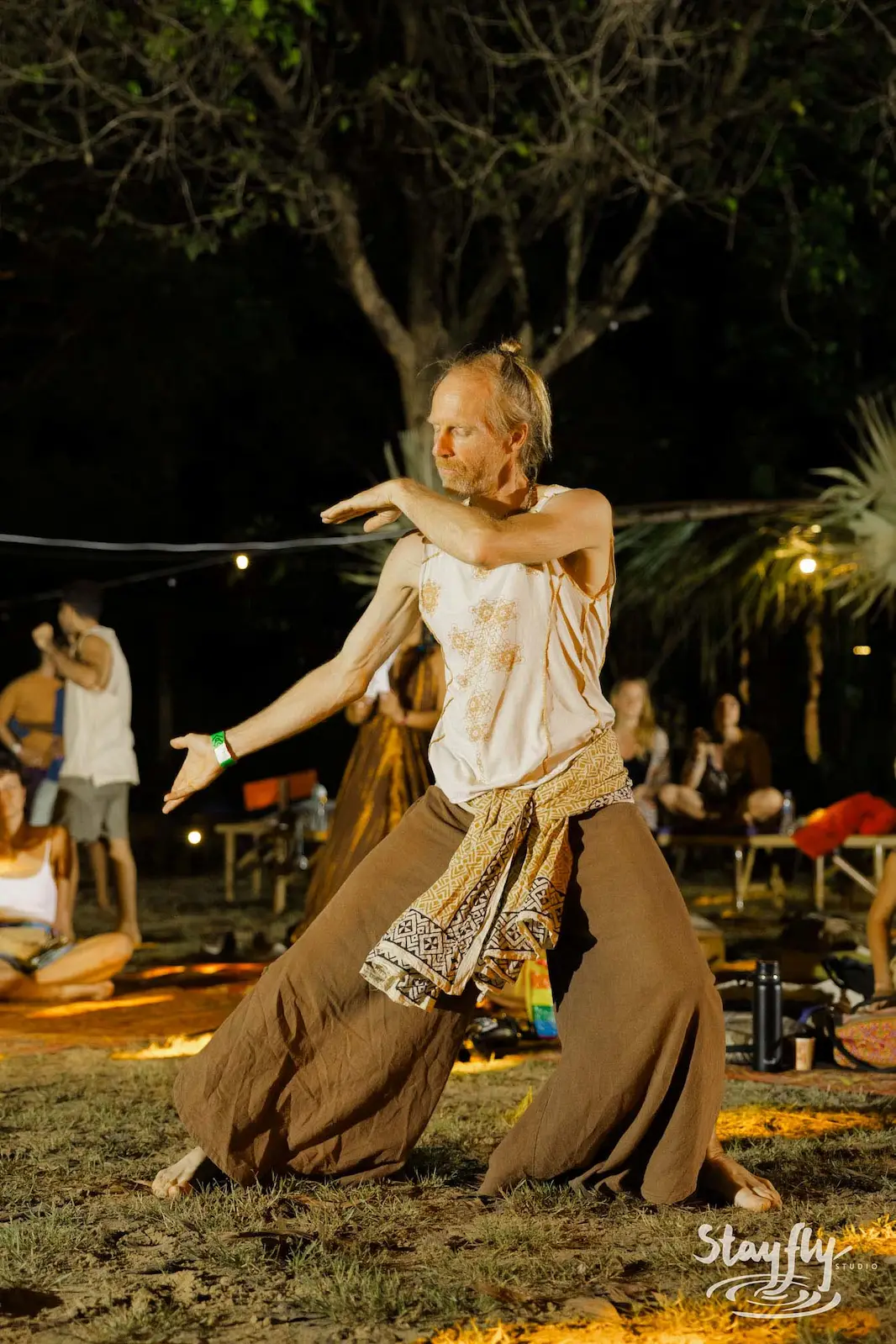 Person dancing outdoors at night in loose pants.