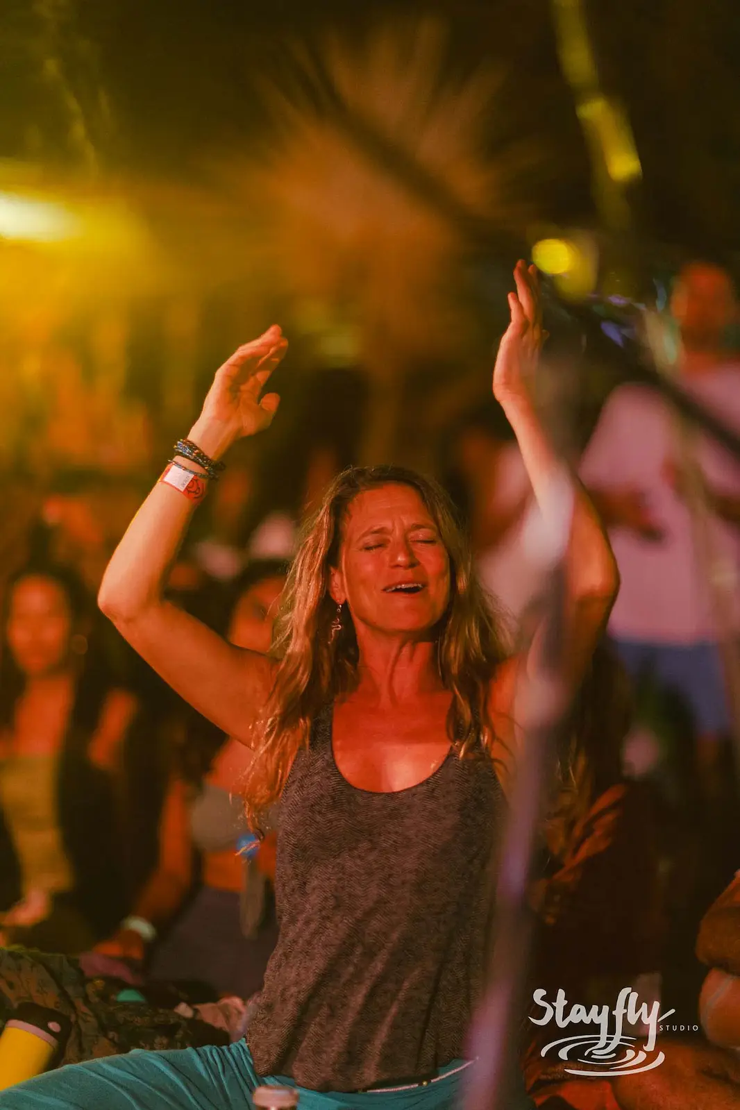 Woman dancing with raised arms at night.