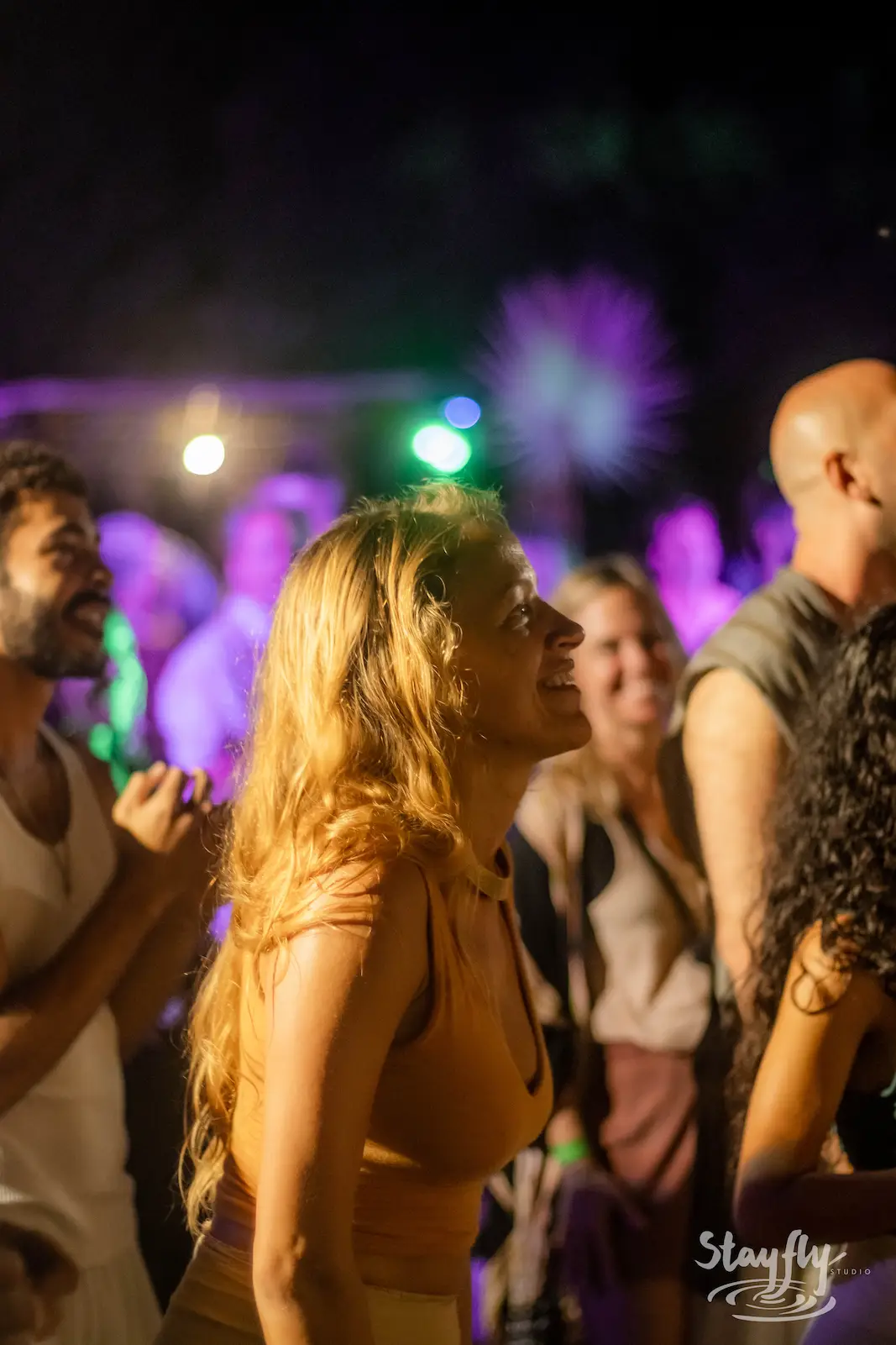 Woman smiling amid crowd at night party.