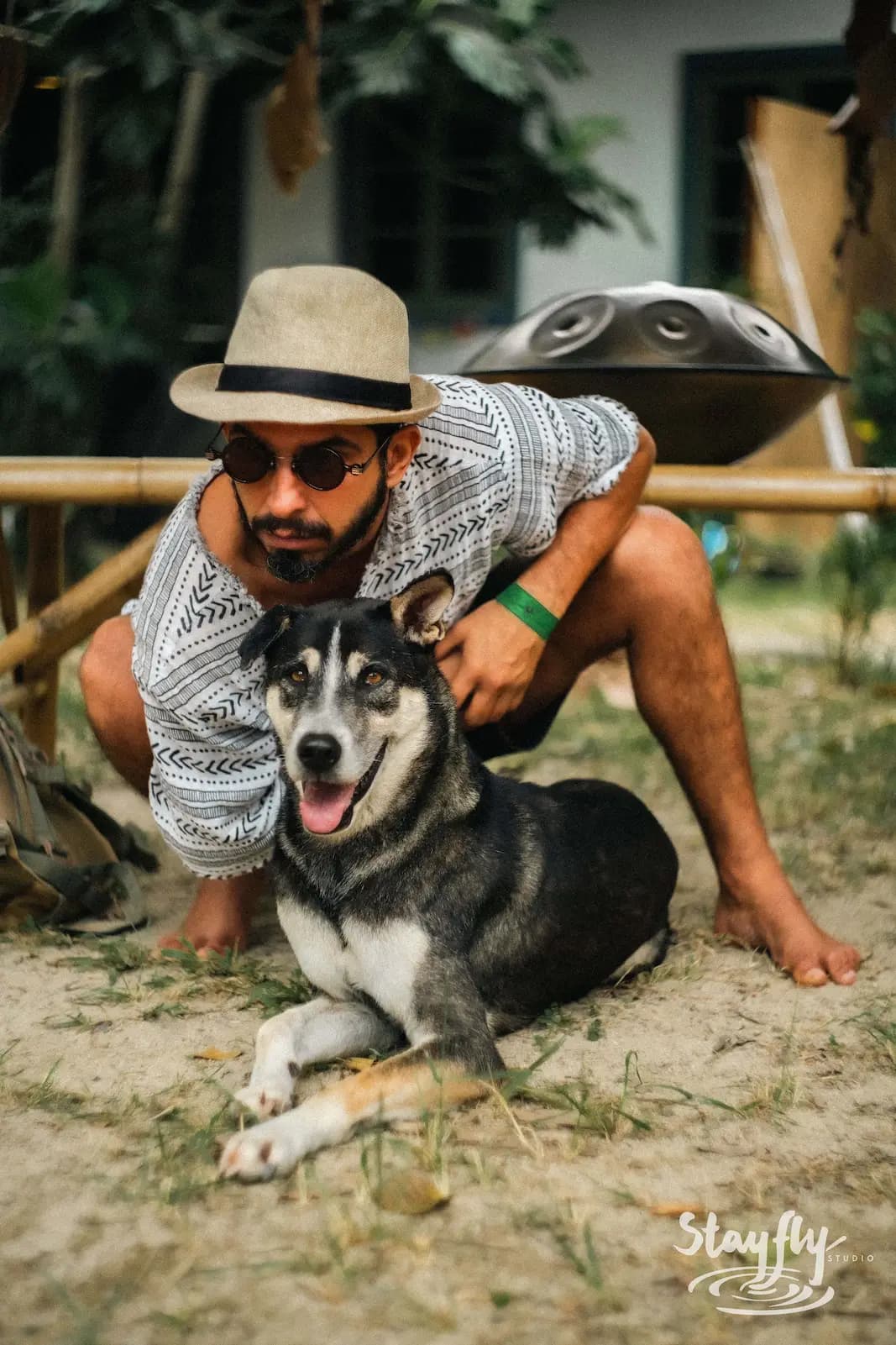 Man crouching with husky dog outdoors.