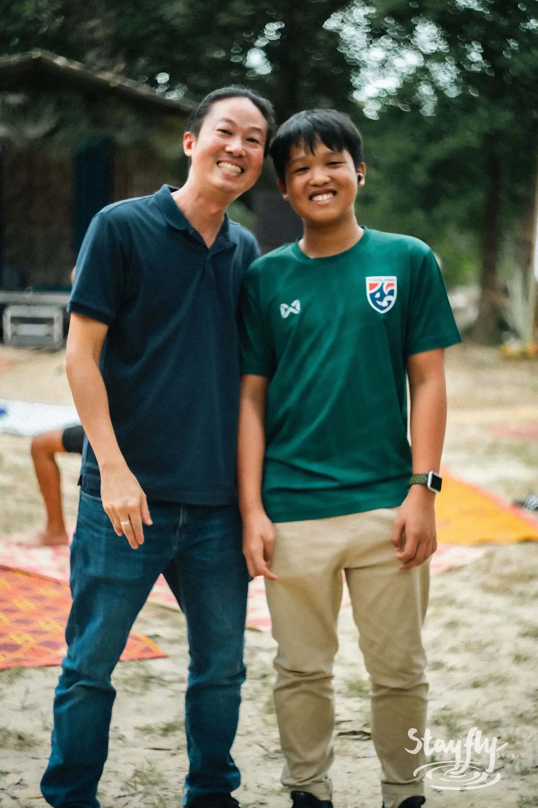 Two men posing together, one in green shirt.