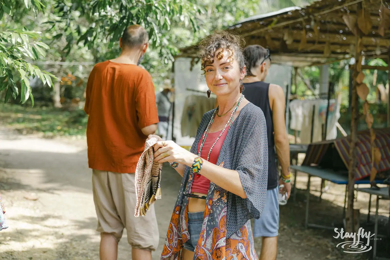 Smiling woman outdoors holding scarf, daytime.