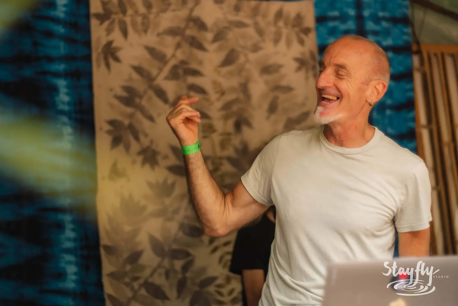Man laughing in front of indigo-dyed fabric backdrop.