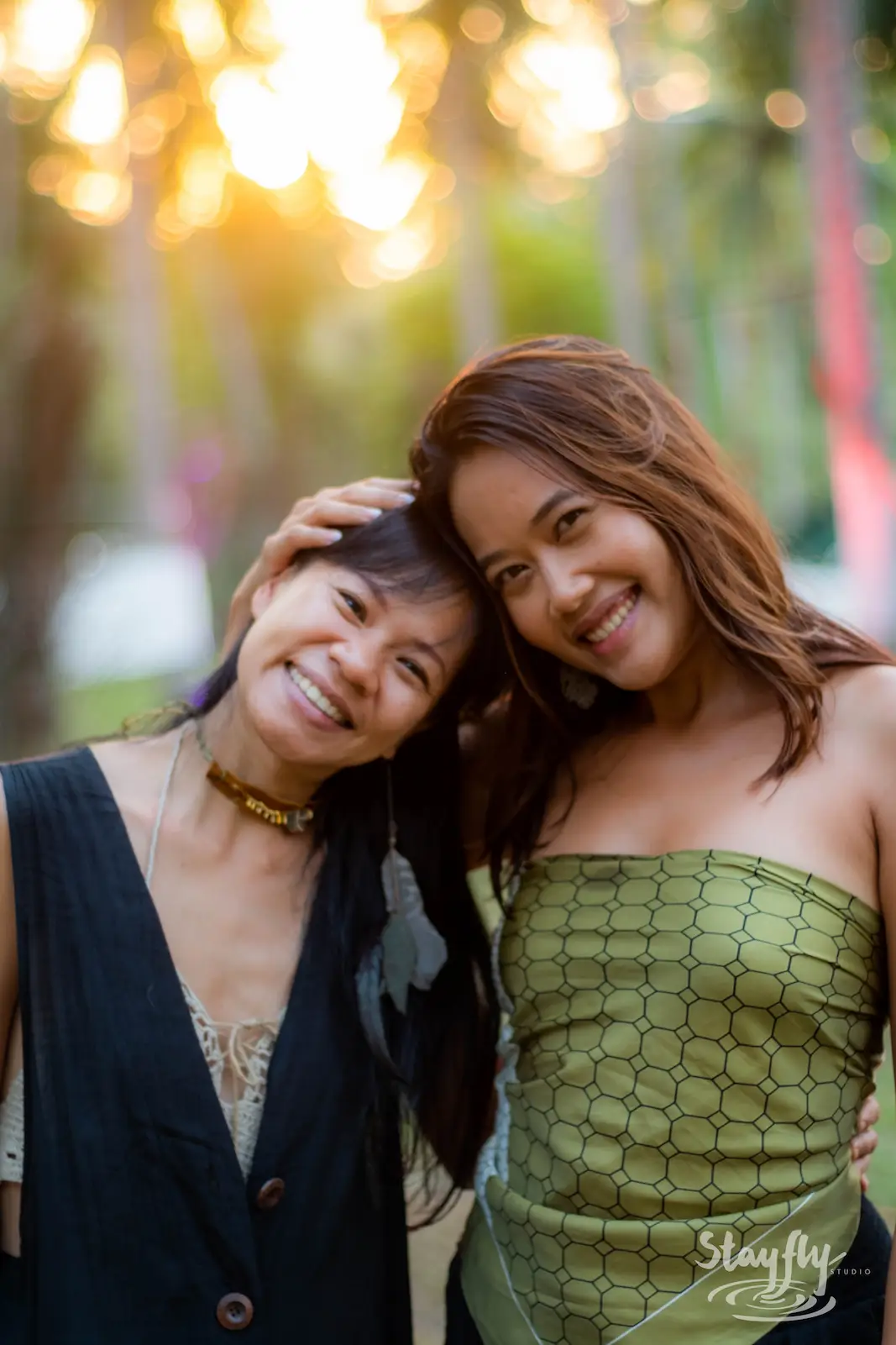 Two women embracing among trees at sunset.