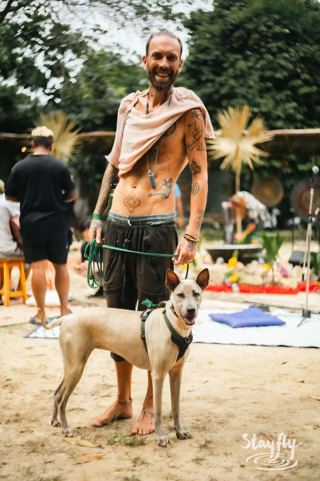 Tattooed man standing with his dog.