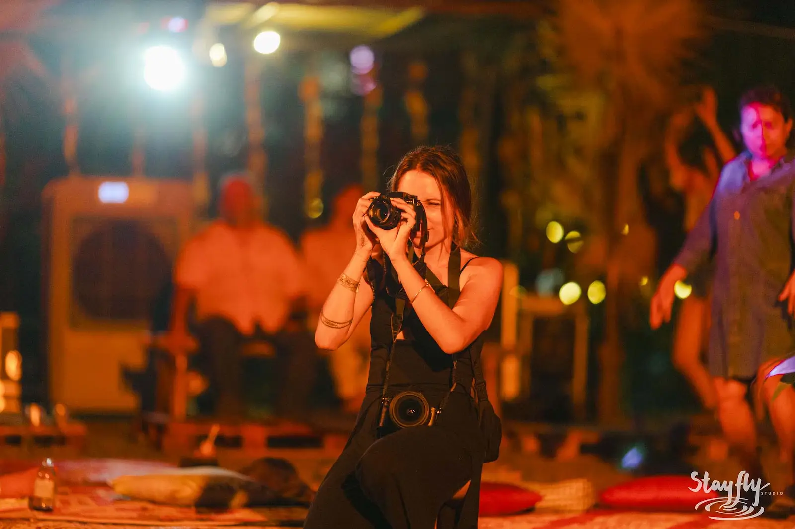 Woman photographer kneeling with camera at night.