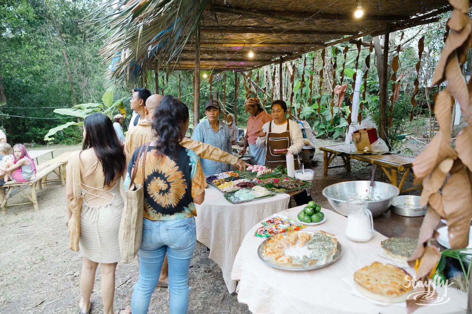 Buffet food service under canopy with people lining up.