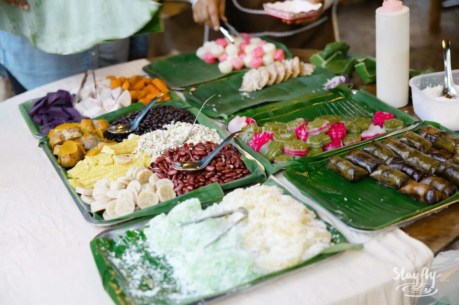 Assorted Thai desserts and food on banana leaves.