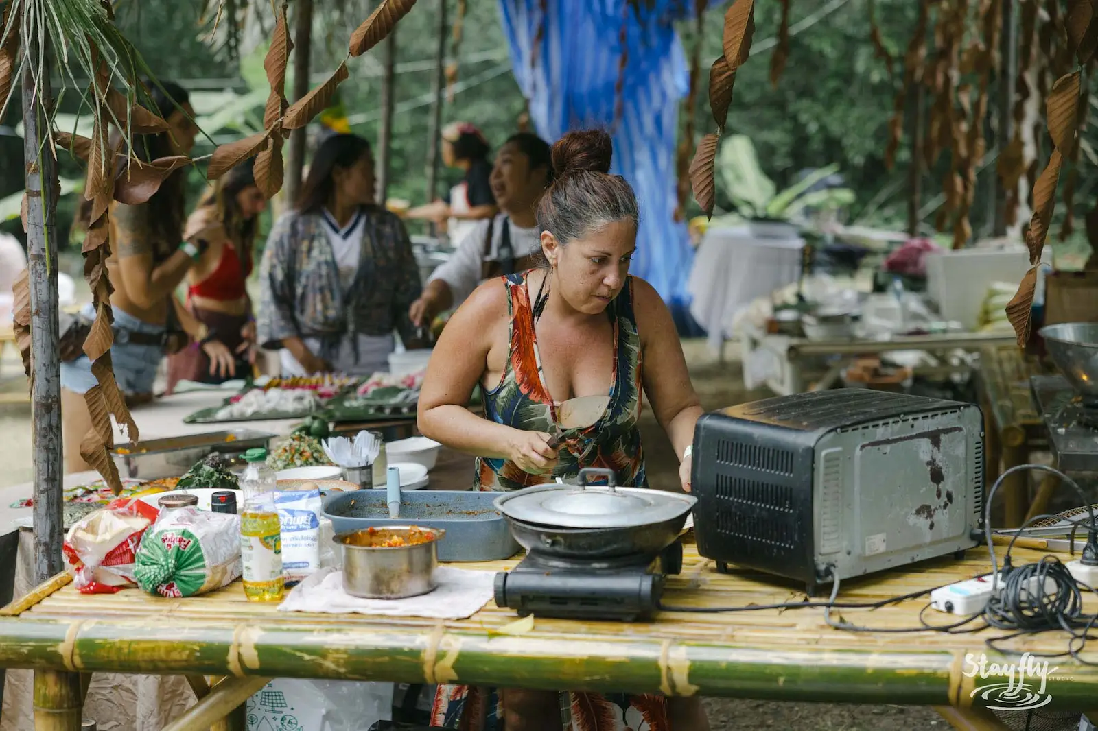 Woman cooking at outdoor kitchen station.