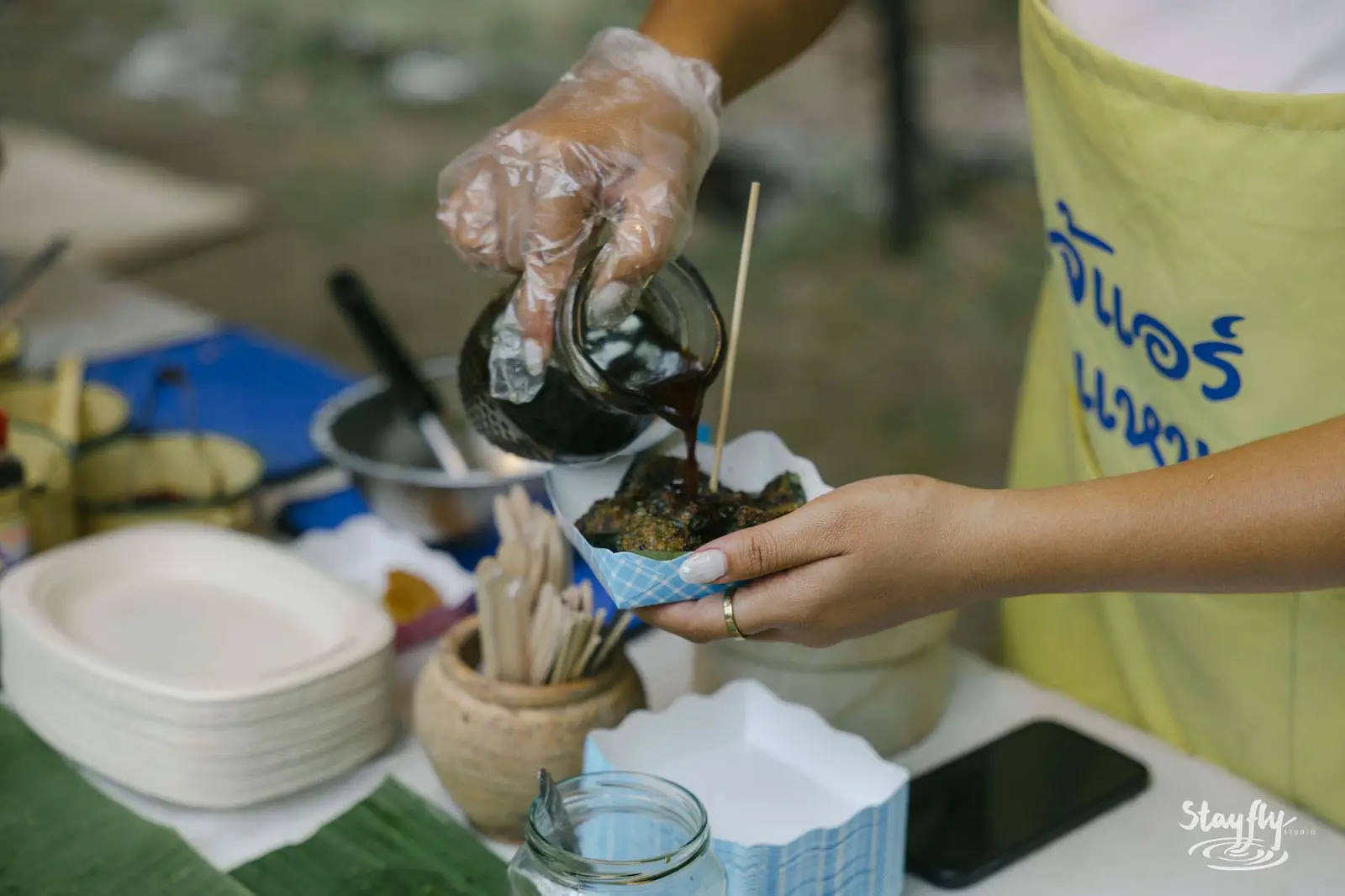 Vendor pouring sauce at food stall.