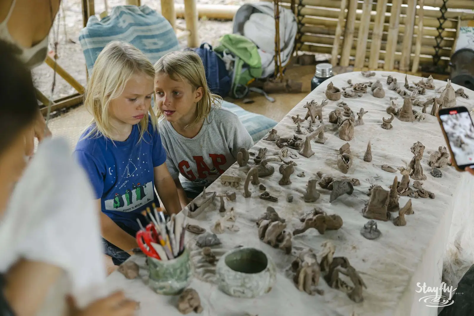 Two girls sculpting clay figures at a table.