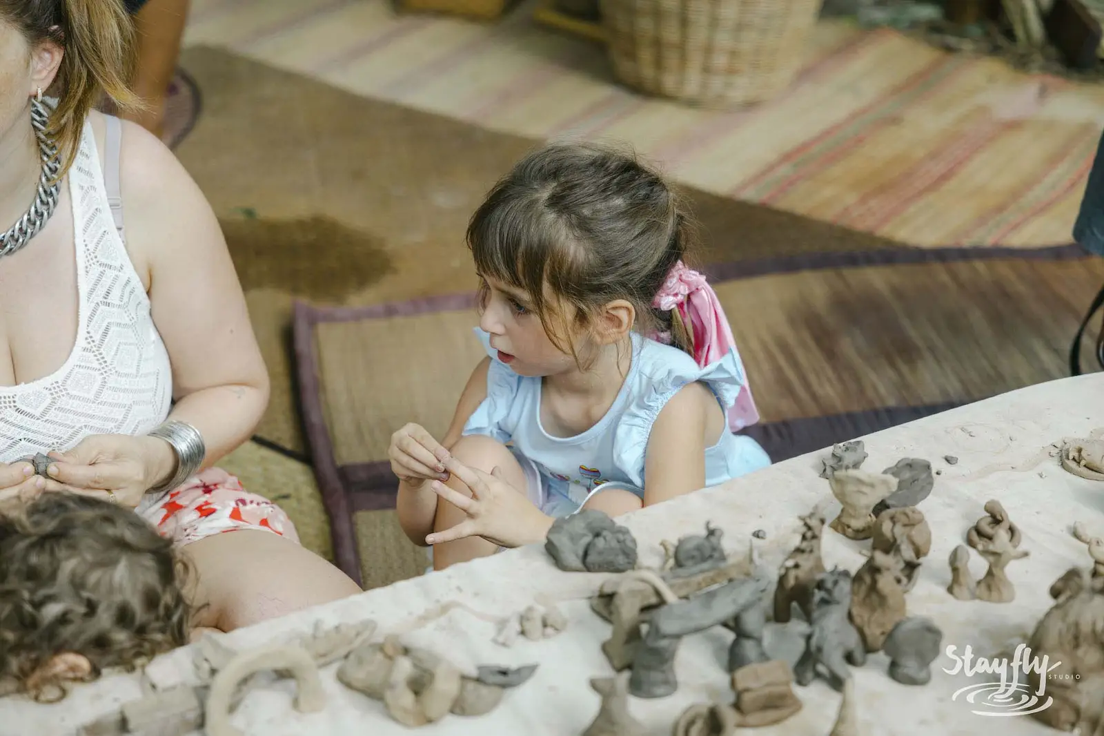Children making clay figures at workshop table.
