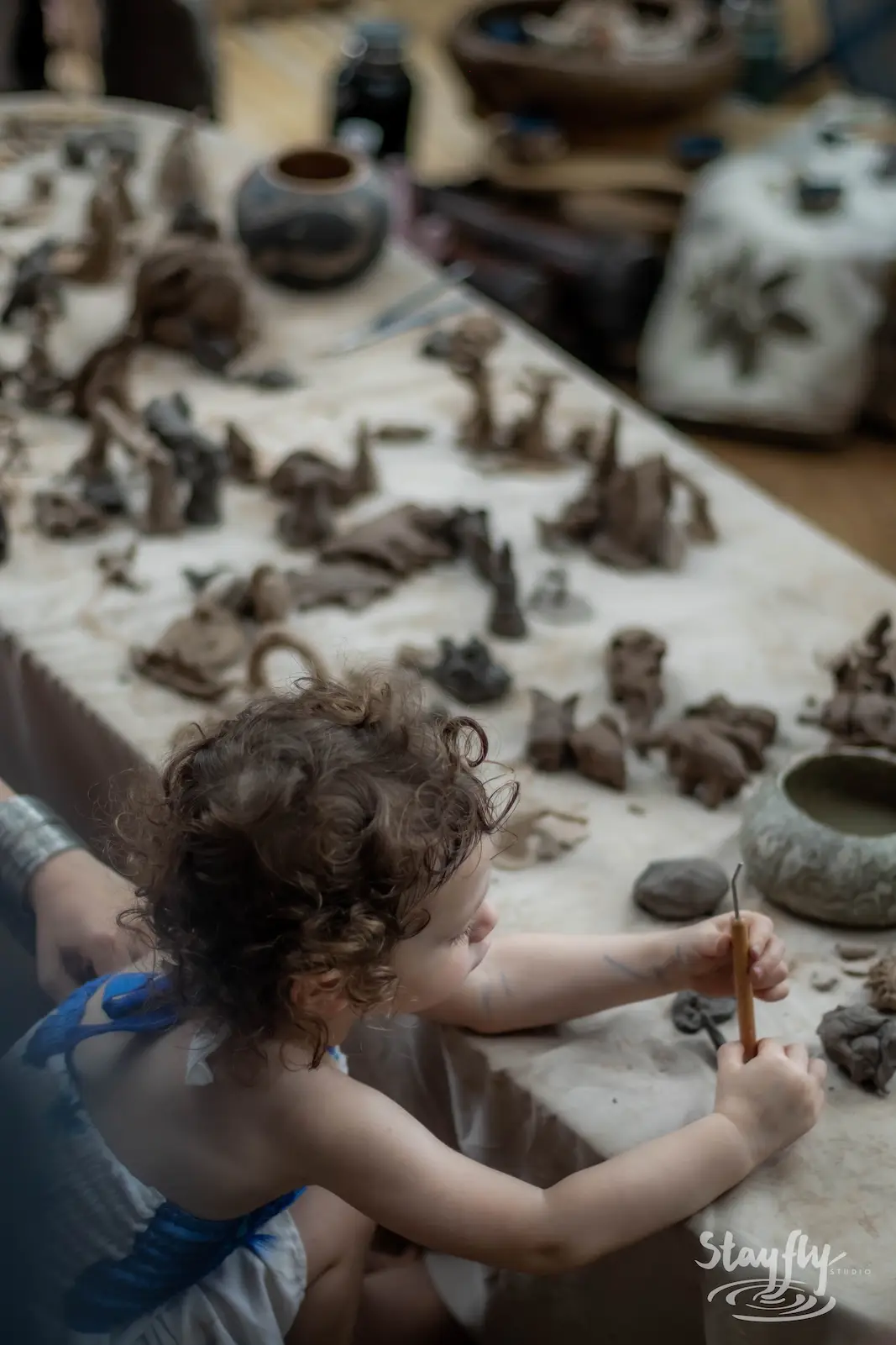 Child shaping clay figures at craft table.