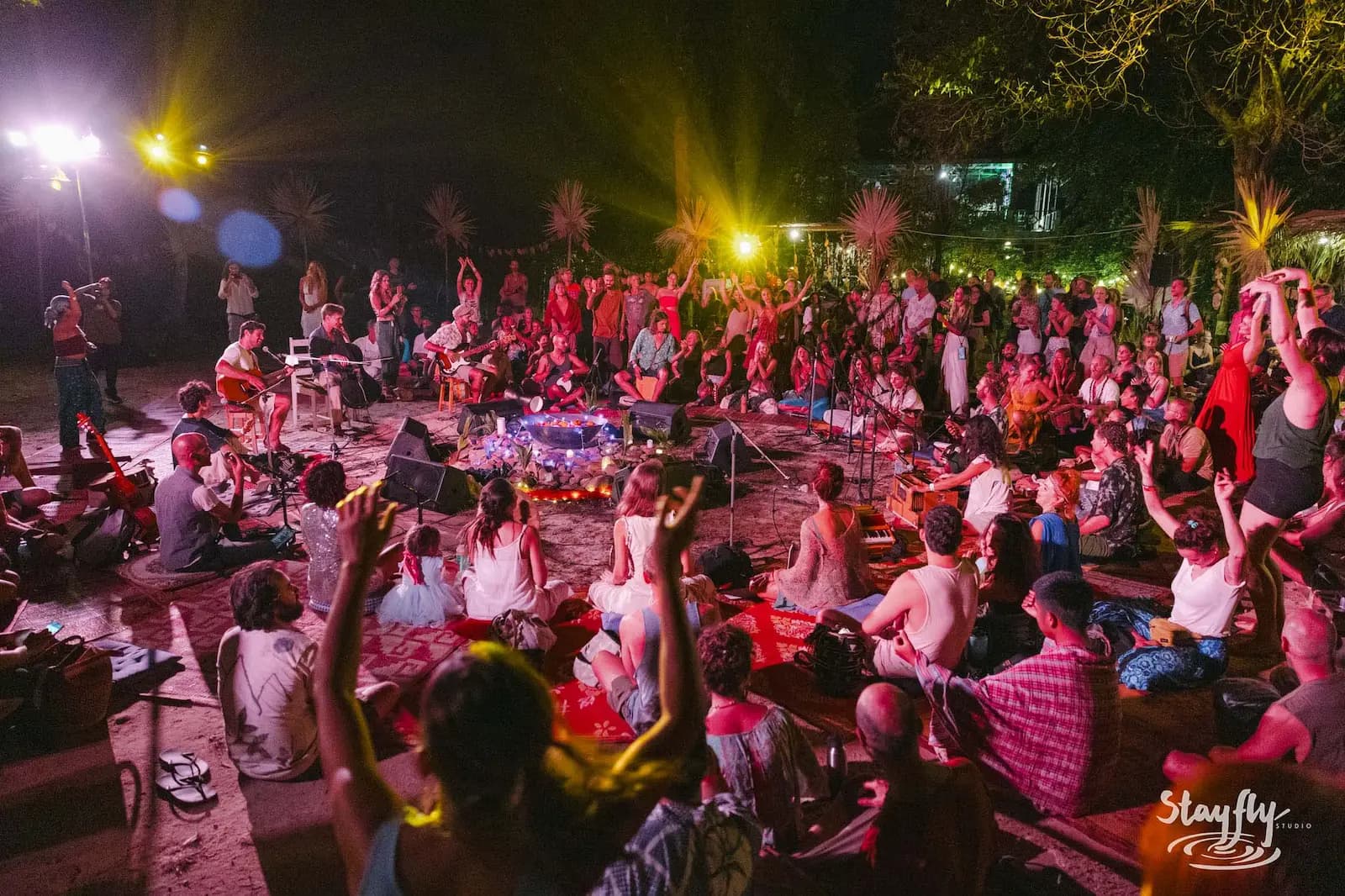 Large seated night crowd around band, warm red lighting.