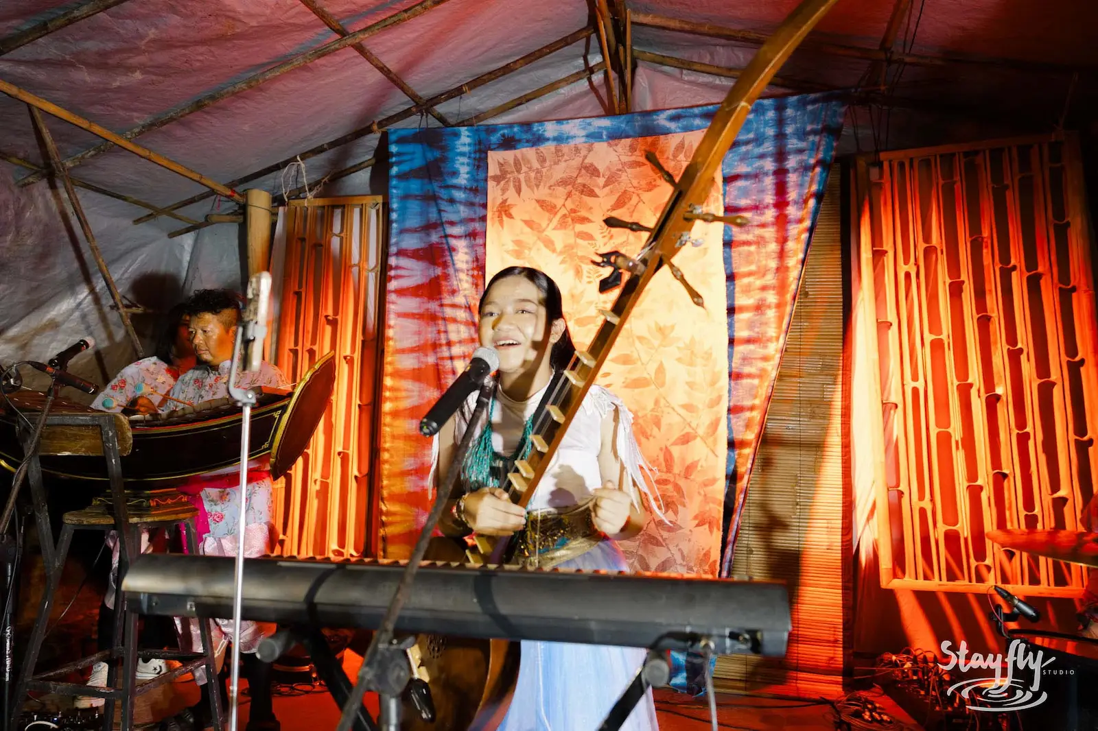 Singer performing at tie-dye backdrop tent stage.
