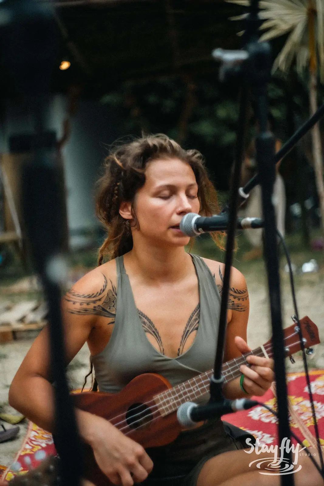 Tattooed woman playing ukulele and singing.