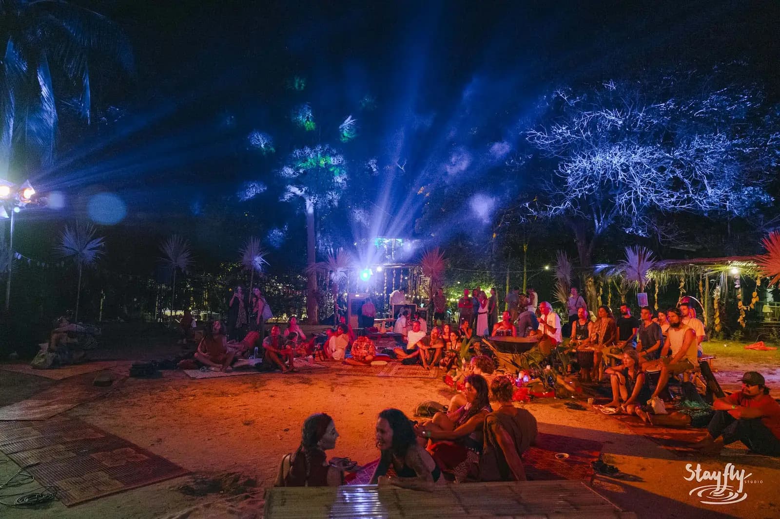 Night crowd under blue laser light beams.
