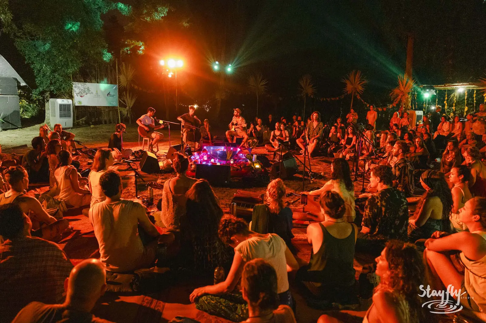 Band performs for seated crowd under red light.
