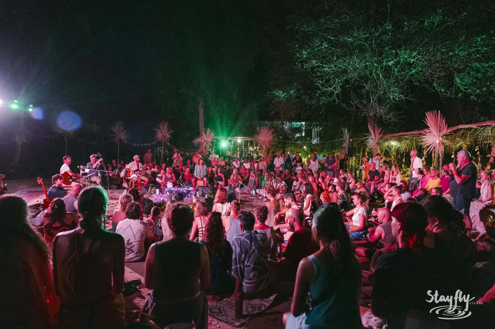 Crowd gathered around fire-lit stage at night.