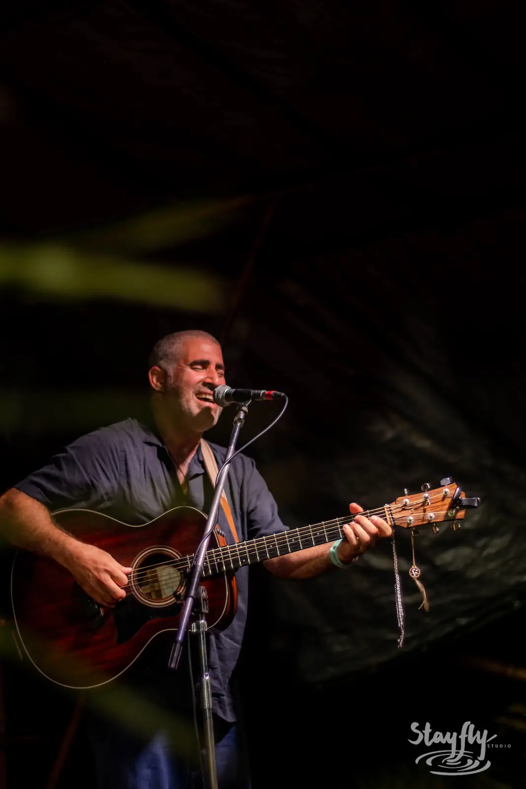 Guitarist singing into microphone on stage.