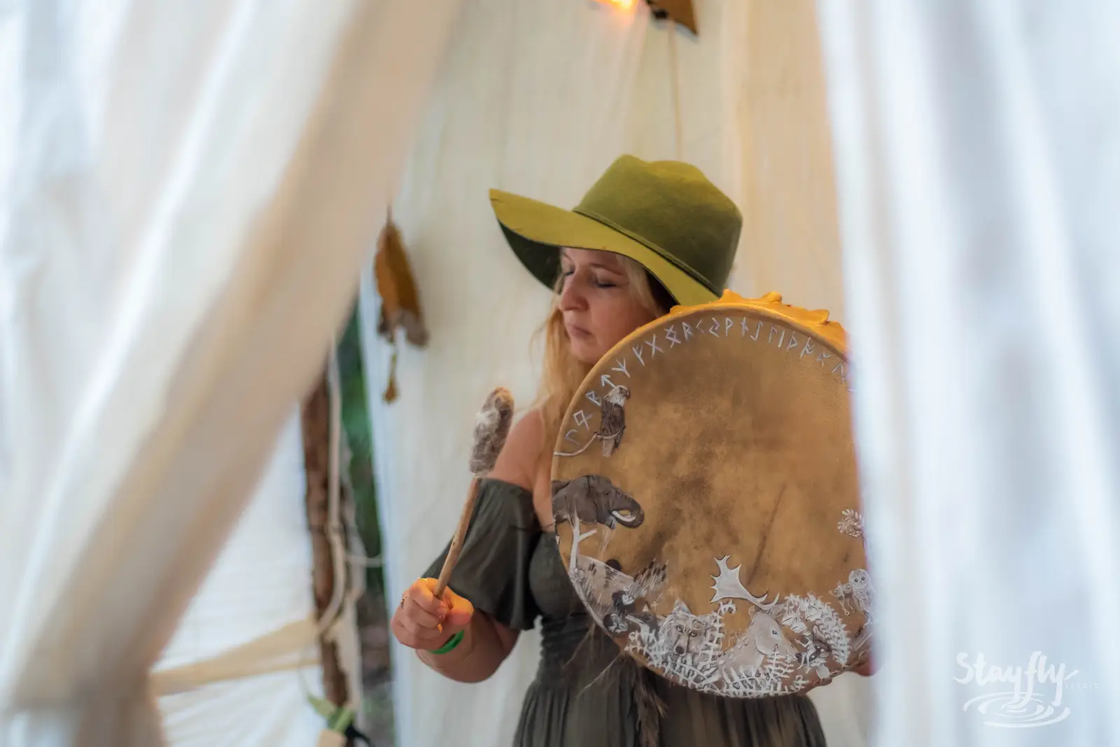 Woman in wide-brim hat holding a frame drum.