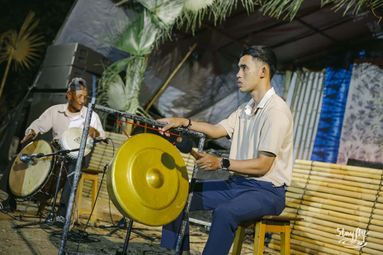 Two men playing gong and drum at night.