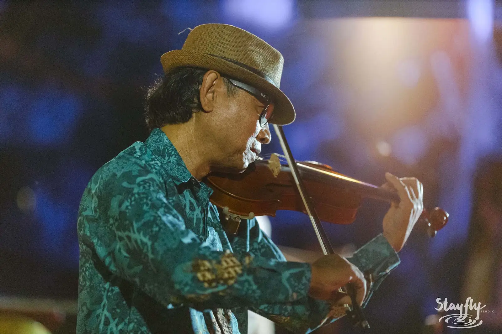 Older man in hat playing violin.