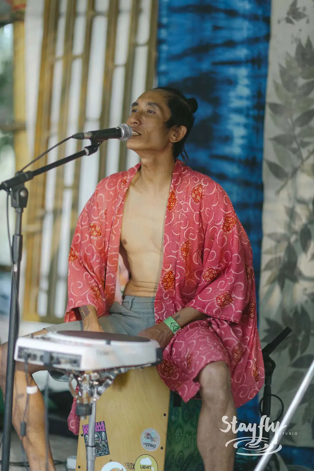 Man in red robe singing while playing keyboard.