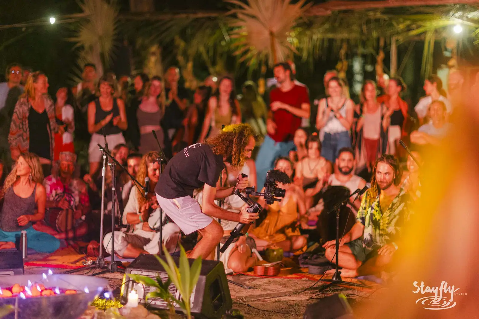 Musician performing to seated crowd by candlelight.