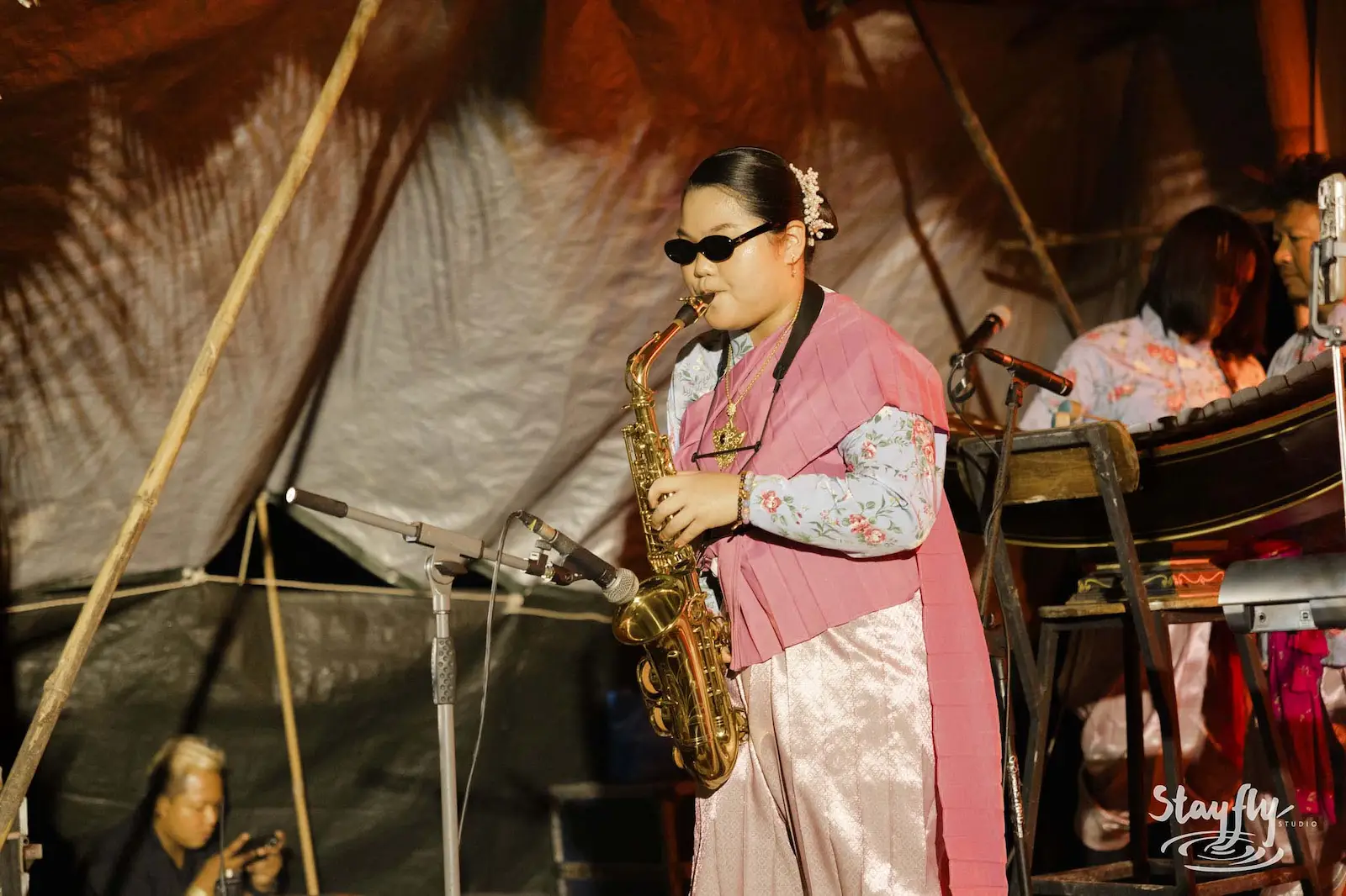 Saxophonist in pink traditional dress performing on stage.