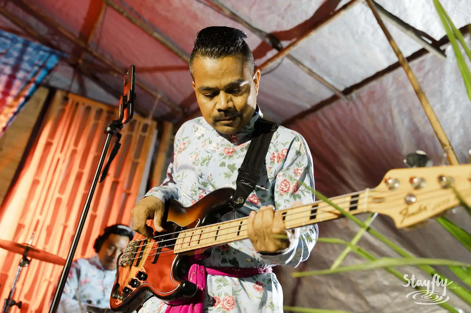 Bassist in traditional shirt performing on stage.