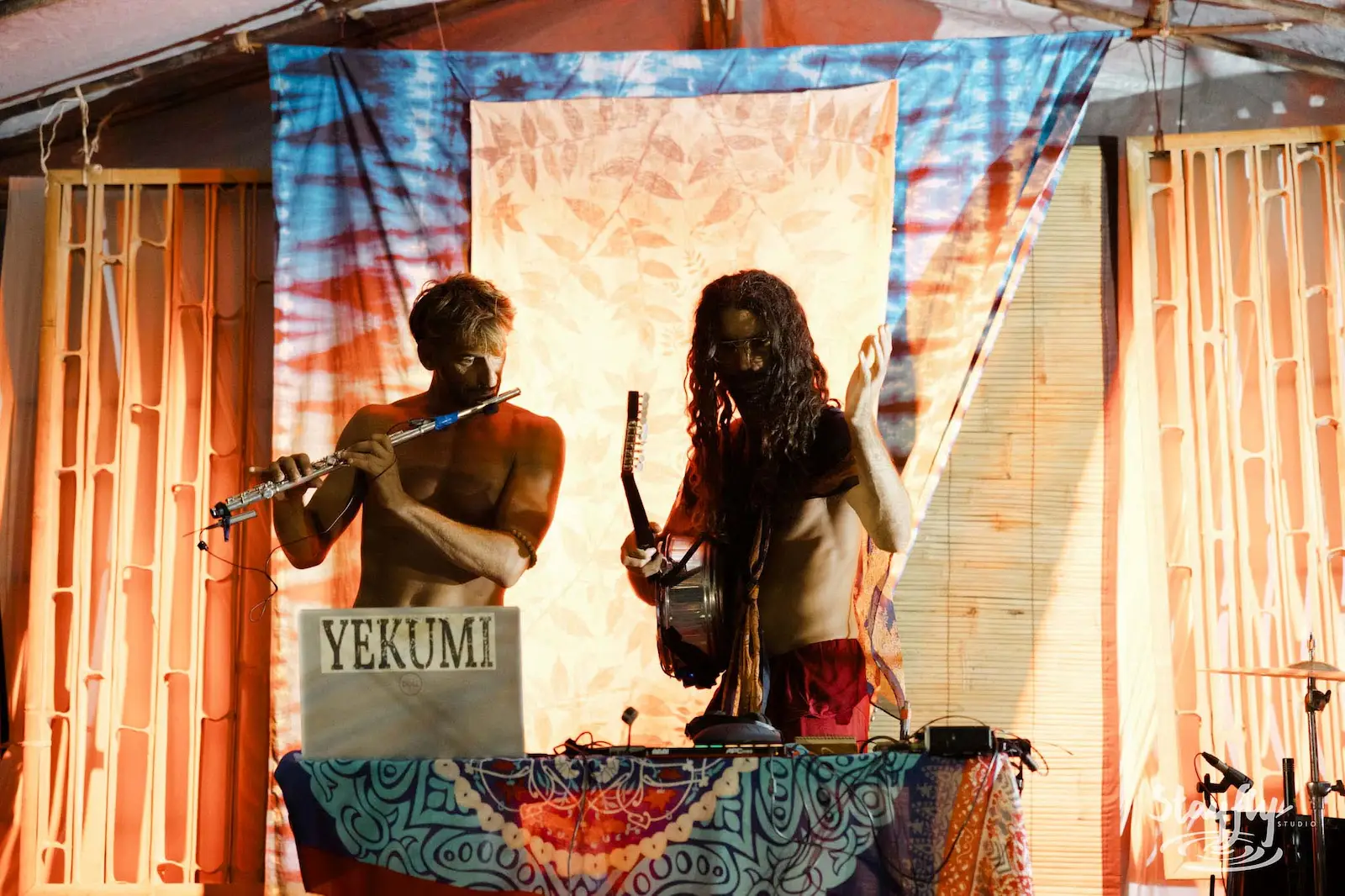 Duo performers Yekumi on stage with tie-dye backdrop.