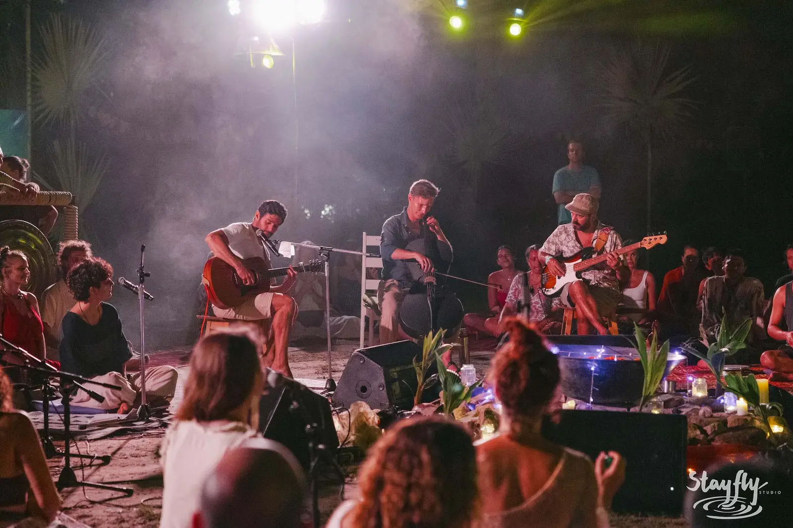 Three musicians performing in circle at night stage.