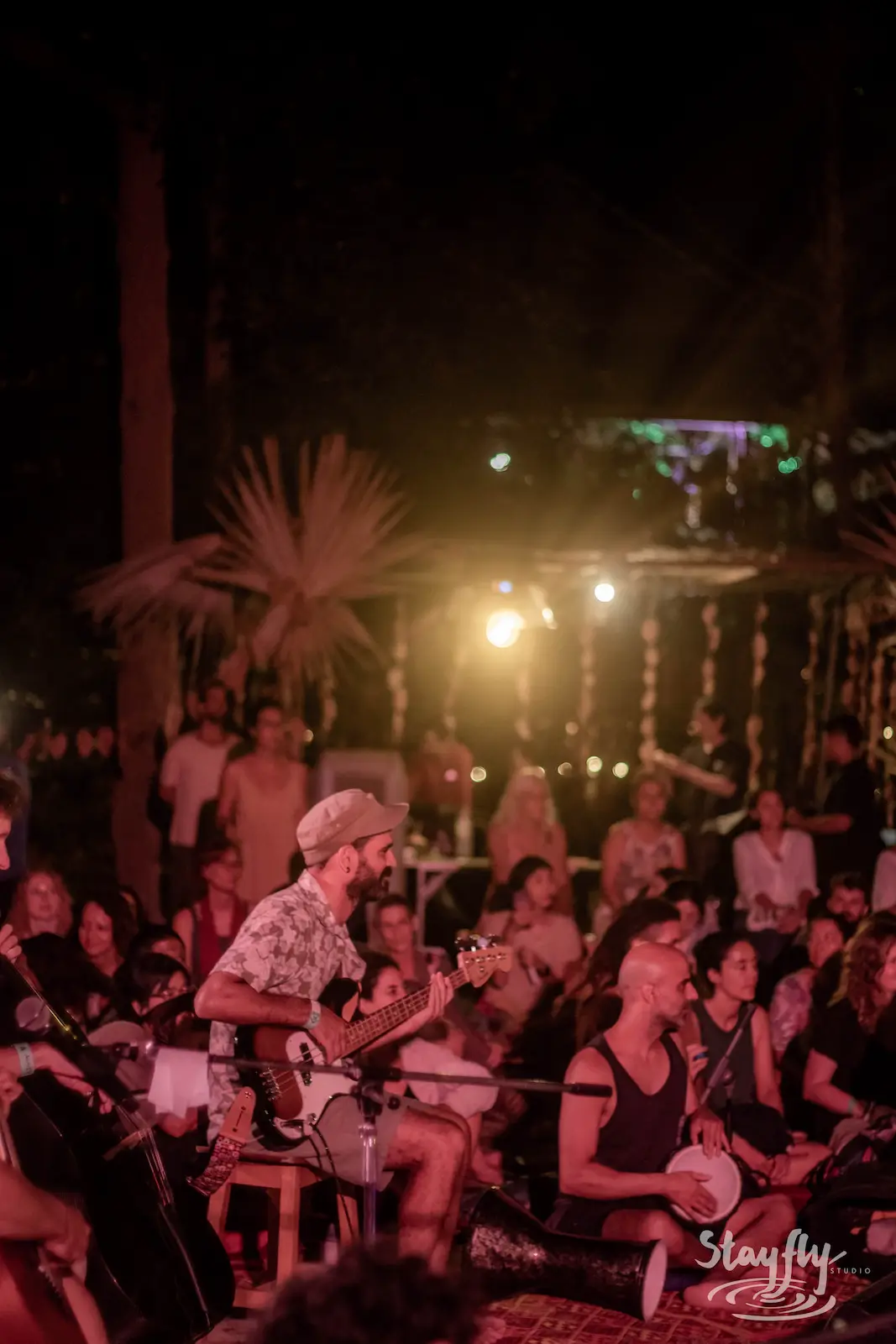 Guitarist performing before seated crowd at night.