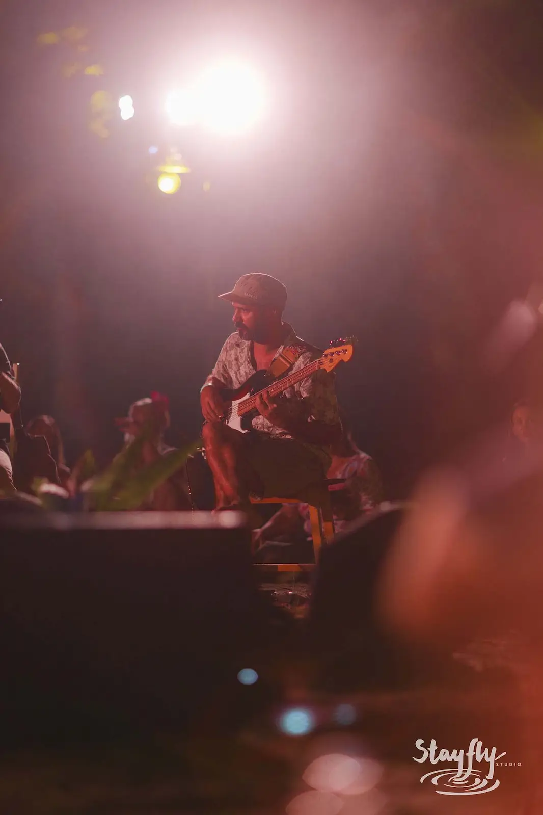Guitarist silhouetted on small night stage.