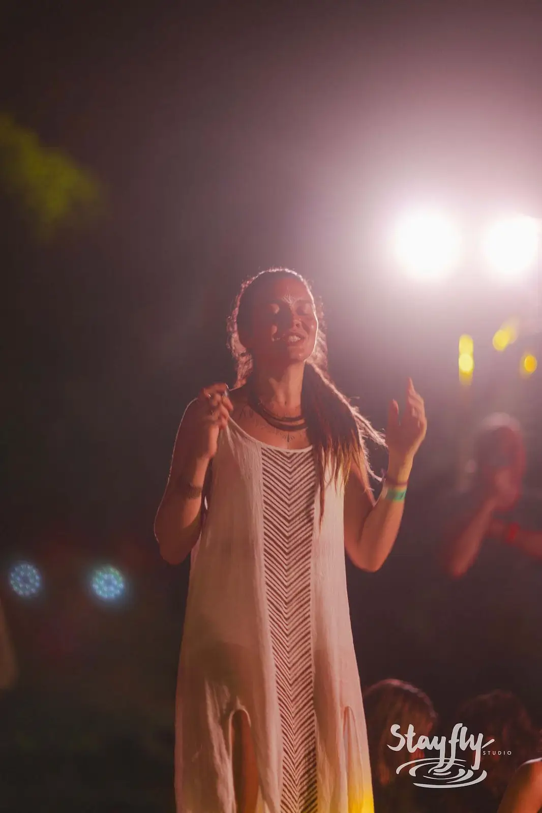 Woman singing at night microphone in white dress.