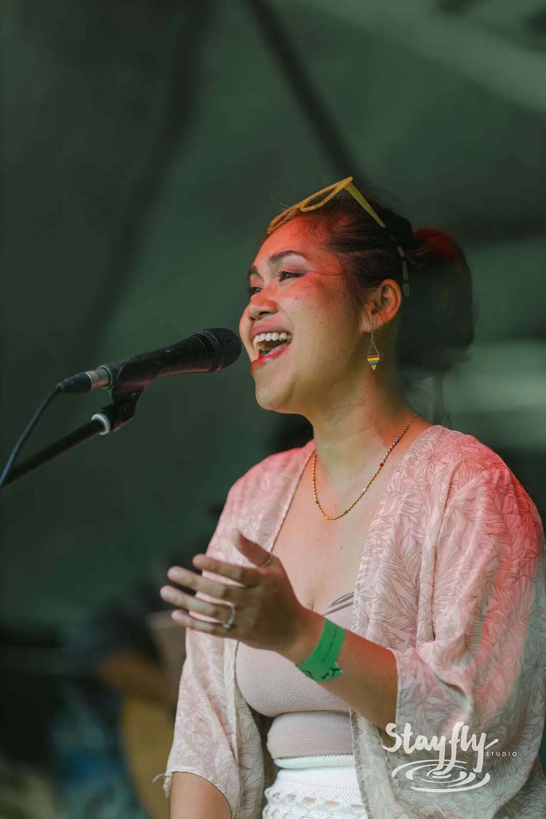 Woman singing on daytime stage, orange face paint.